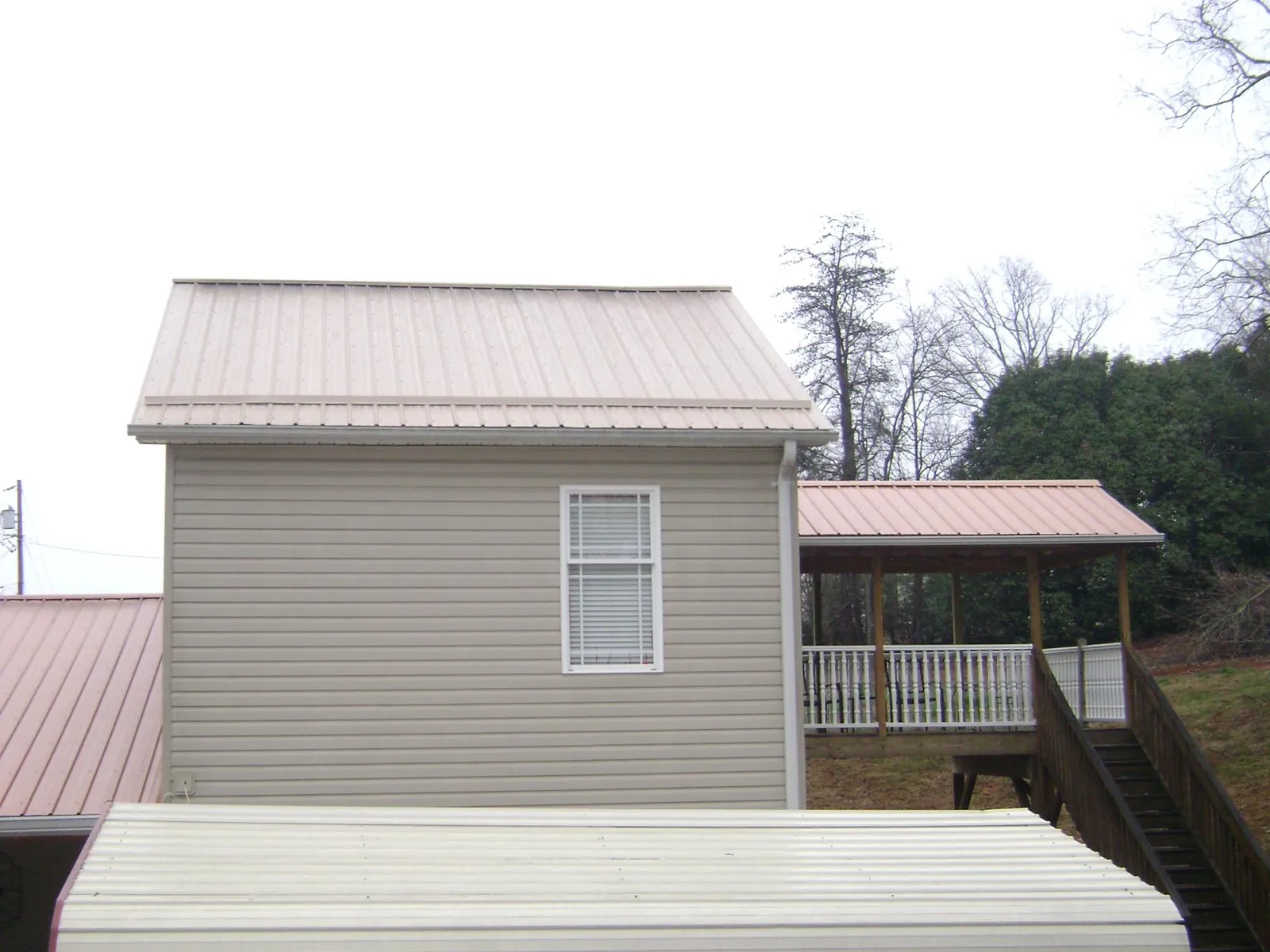 Tan metal roofs on a two story addition and attached porch, from a Roof Replacement job in Kingstree